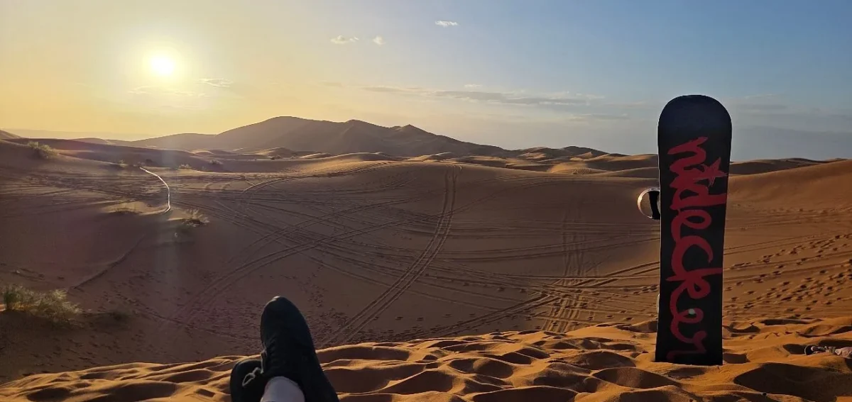 Sandboarding at sunset in the Erg Chebbi dunes during a 2 days desert tour from Marrakech to Fes via Merzouga.