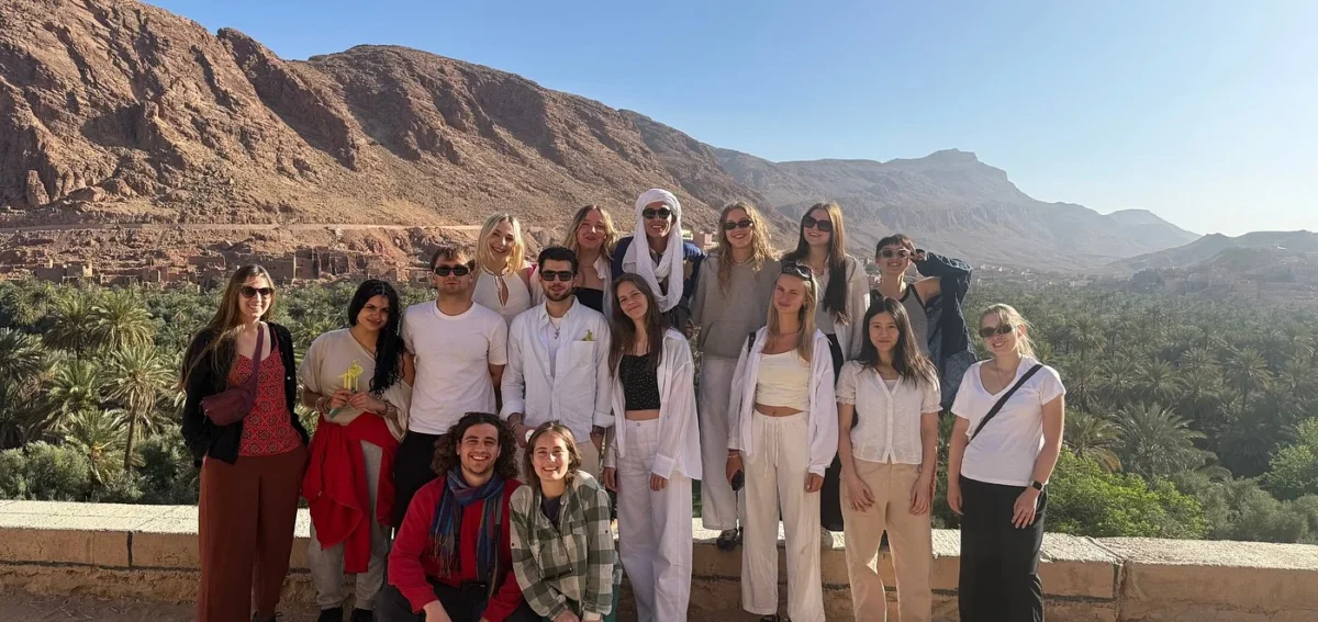 Group of travelers enjoying a panoramic view of Todra Gorge and the Tinghir palm oasis during a Morocco desert tour.