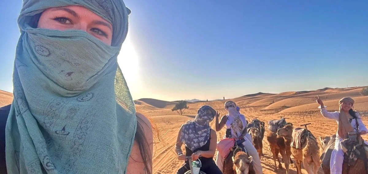 Travelers enjoying a camel ride in Erg Chebbi dunes during the 5 days desert tour from Marrakech to Fes via Merzouga