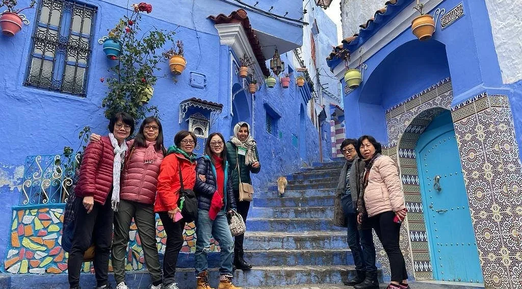 Travelers in the blue streets of Chefchaouen during a 7 days Morocco tour from Casablanca