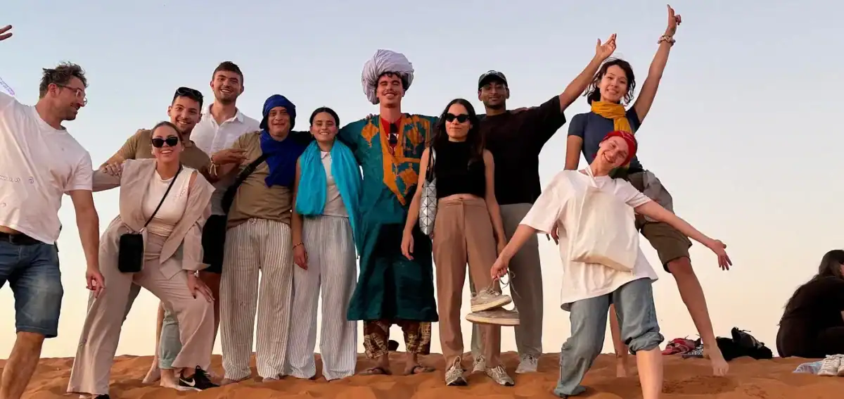 Travelers group photo in Merzouga Sahara during a 4 days tour from Fes to Marrakech