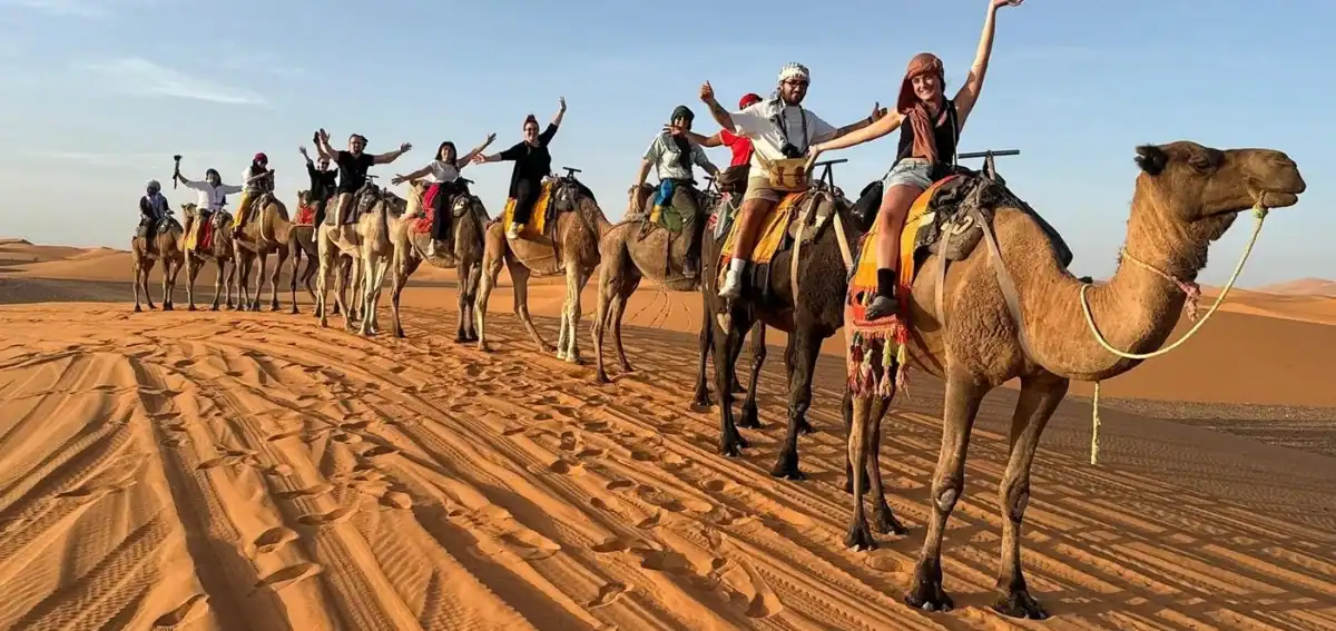group-camel-caravan-erg-chebbi-4-days-fes-merzouga Group camel caravan crossing Erg Chebbi dunes on a 4 days Fes to Merzouga desert tour