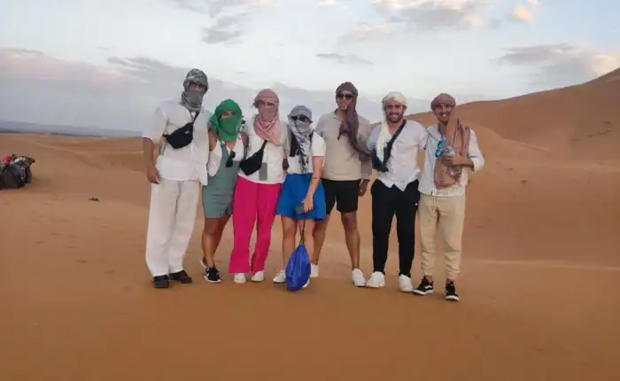 Group photo in the Erg Chebbi dunes near Merzouga during a 5-day tour from Fes to Marrakech