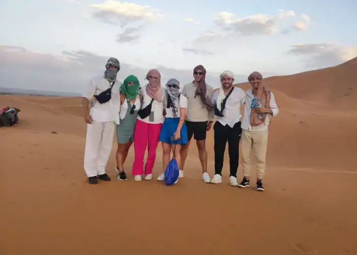 Foto di gruppo tra le dune dell'Erg Chebbi vicino a Merzouga durante un tour di 5 giorni da Fes a Marrakech