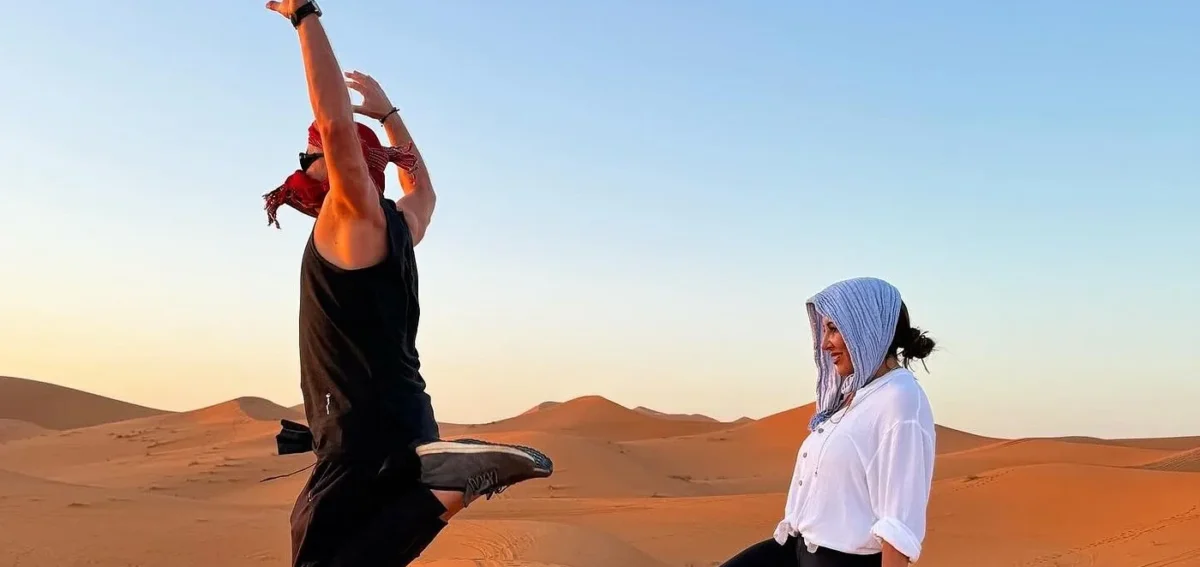 Viaggiatori sulle dune di sabbia dell'Erg Chebbi a Merzouga al tramonto durante un tour del deserto di 7 giorni da Agadir