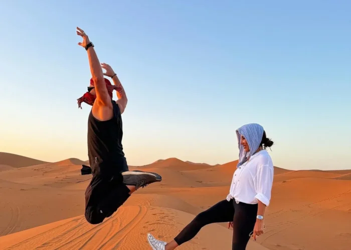 Viajeros en las dunas de arena de Erg Chebbi en Merzouga al atardecer en un tour de 7 días por el desierto desde Agadir