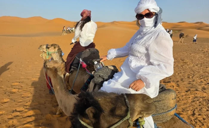 Traveler riding a camel across the Erg Chebbi dunes during the 4-day Agadir to Merzouga desert tour ending in Marrakech
