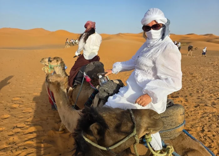 Viajero montando en camello por las dunas de Erg Chebbi durante el tour de 4 días por el desierto de Agadir a Merzouga con final en Marrakech