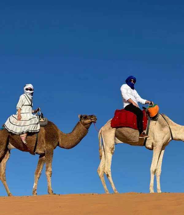 Viajeros montando en camello por las dunas de Erg Chebbi durante un tour por el desierto de 7 días de Tánger a Marrakech