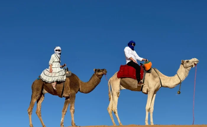 Viajeros montando en camello por las dunas de Erg Chebbi durante un tour por el desierto de 7 días de Tánger a Marrakech
