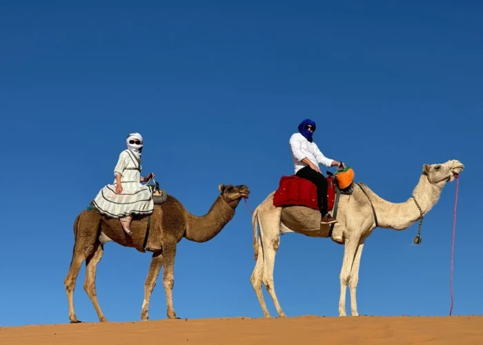 Viajeros montando en camello por las dunas de Erg Chebbi durante un tour por el desierto de 7 días de Tánger a Marrakech