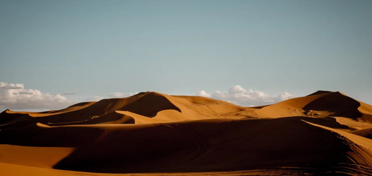 Merzouga desert dunes panorama with golden sand and blue sky in Morocco