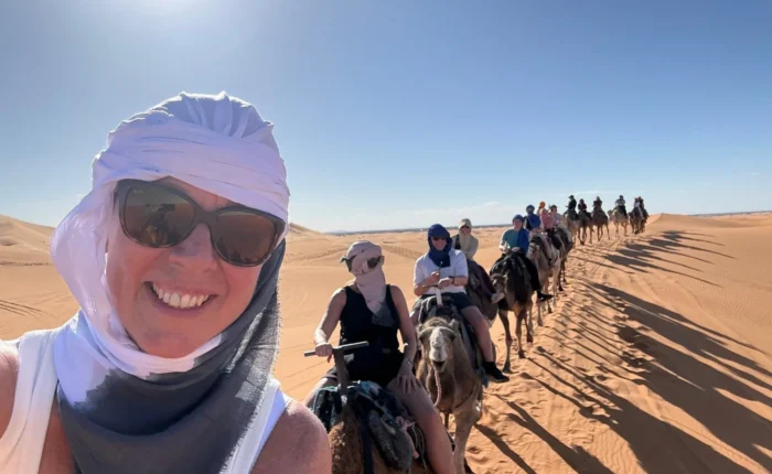 Viaggiatori che cavalcano cammelli nel Deserto del Sahara di Merzouga durante un tour di 3 giorni da Ouarzazate a Marrakech