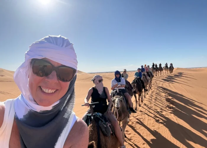Travelers riding camels in the Merzouga Sahara Desert during a 3 days tour from Ouarzazate to Marrakech