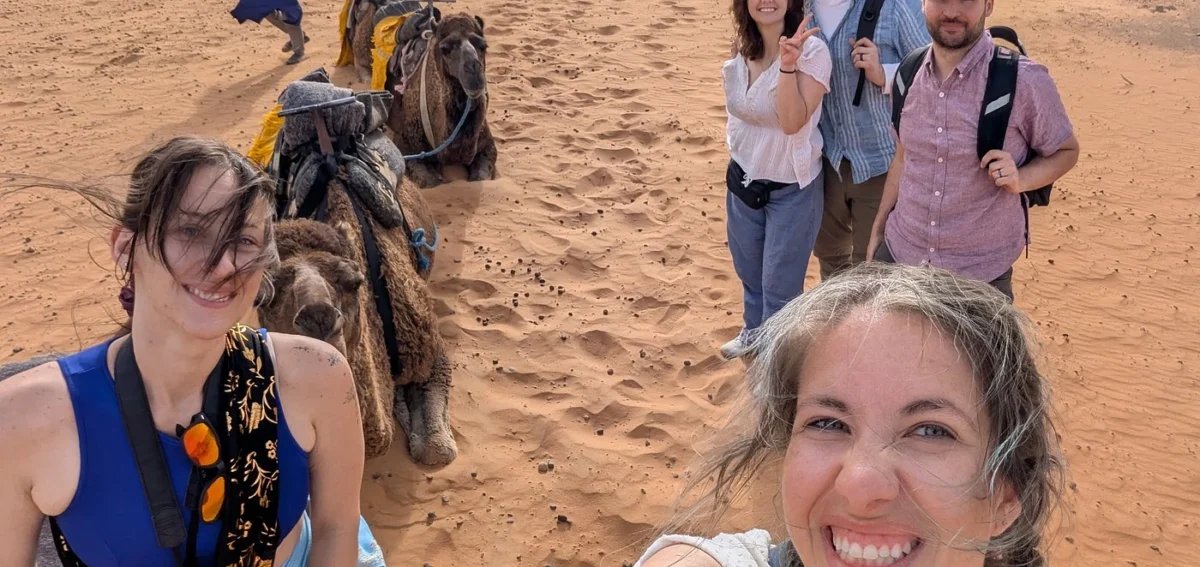 Travelers enjoying a camel trek in Erg Chebbi dunes during a 7 days Morocco tour from Rabat to Marrakech.