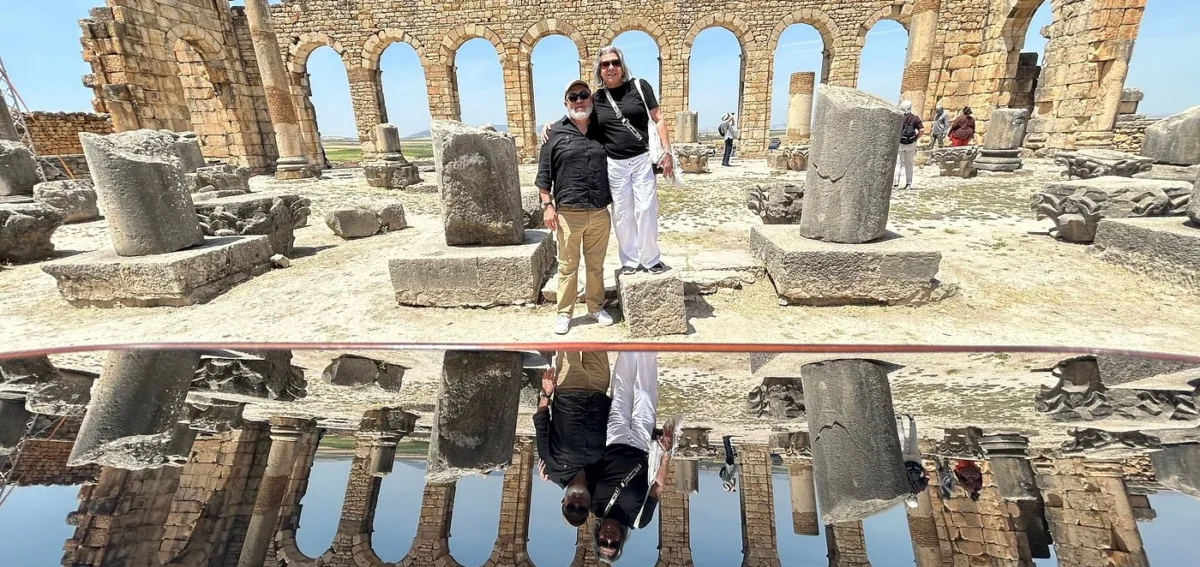 Travelers visiting Volubilis Roman ruins during a 7 days Morocco tour from Rabat to Marrakech.