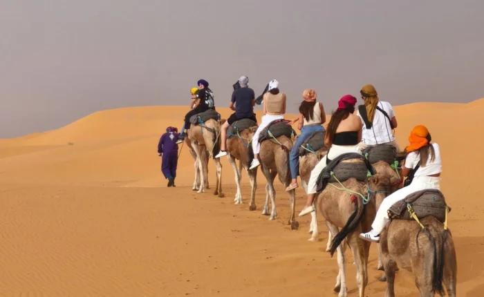 Viajeros montando en camello por las dunas de Erg Chebbi durante un tour al desierto de Merzouga