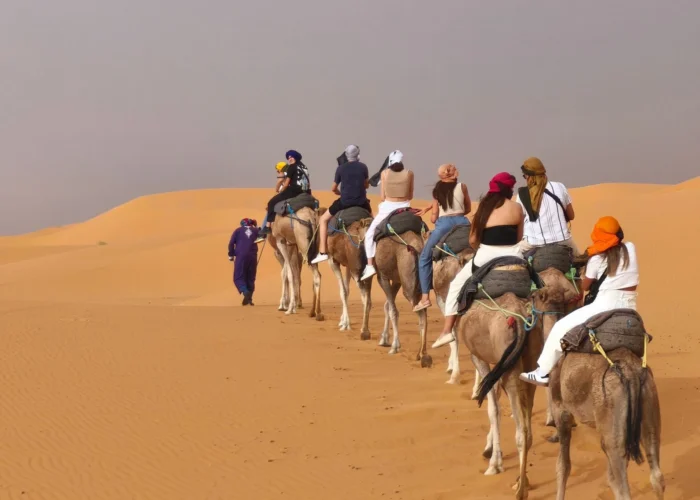 Viajeros montando en camello por las dunas de Erg Chebbi durante un tour al desierto de Merzouga